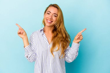 Mavi arka planda izole edilmiş beyaz kadın farklı kopya alanlarını gösteriyor, birini seçiyor, parmaklarıyla gösteriyor.