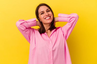 Sarı arka planda izole edilmiş, kollarını uzatan, rahat bir pozisyonda genç beyaz bir kadın..