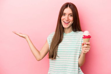 Pembe arka planda dondurmayı tutan beyaz bir kadın bir avuç içinin fotokopi çektiğini ve diğer elini belinde tuttuğunu gösteriyor..