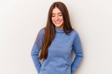 Beyaz arka planda izole edilmiş genç beyaz kadın gülüyor ve gözlerini kapıyor, rahatlamış ve mutlu hissediyor..