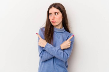 Beyaz arka plan noktalarında izole genç beyaz kadın, iki seçenek arasında seçim yapmaya çalışıyor.