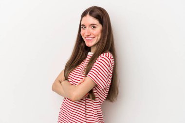 Beyaz arka planda kendini güvende hisseden, kararlılıkla kollarını kavuşturan beyaz tenli genç bir kadın..
