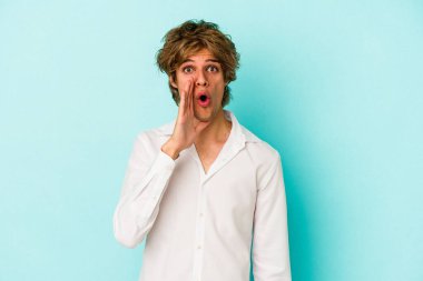 Mavi arka planda izole edilmiş beyaz makyajlı genç bir adam gizli bir sıcak fren haberi veriyor ve yan bakıyor.