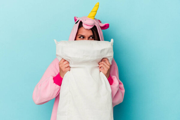 Young caucasian woman wearing an unicorn pajama isolated on blue background