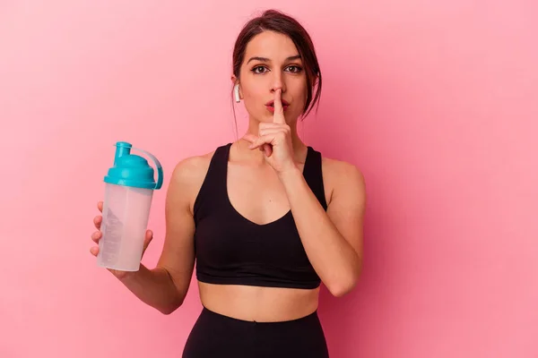 ピンクの背景に単離されたタンパク質シェイクを飲む若い白人女性は秘密を保持するか 沈黙を求めている — ストック写真
