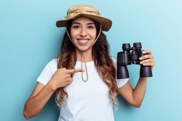 Joven Mexicana Sosteniendo Binoculares Aislados Sobre Fondo Azul Sonriendo Señalando —  Fotos de Stock