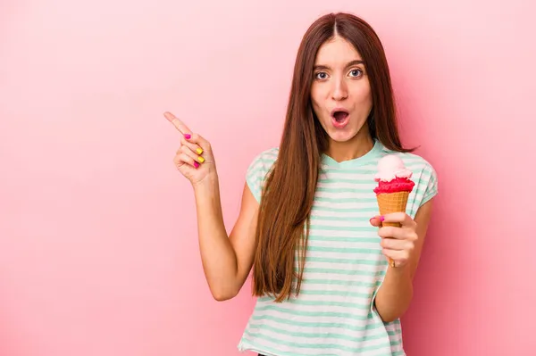 Молодая Белая Женщина Держит Мороженое Розовом Фоне Указывая Сторону — стоковое фото