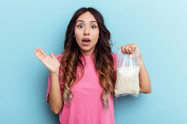 Young Mixed Race Woman Holding Oatmeal Isolated Blue Background Surprised — Stock Photo, Image