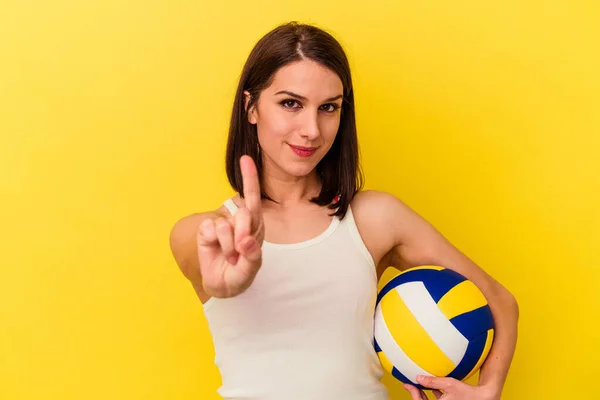 年轻的高加索女子在黄色背景下打排球 表现出第一指尖 — 图库照片