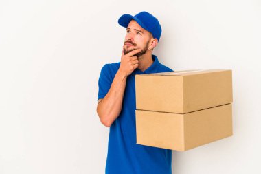 Beyaz arka planda izole edilmiş dövmeleri olan beyaz bir teslimatçı şüpheli ve şüpheci bir ifadeyle yana bakıyor..