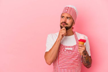 Pembe arka planda dondurması olan beyaz, beyaz bir adam şüpheli ve şüpheci bir ifadeyle yana bakıyor..