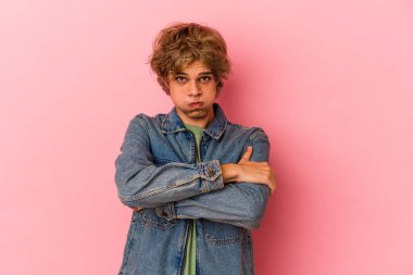 Pembe arka planda izole edilmiş beyaz tenli genç adam yanakları patlatıyor, yorgun bir ifade takınıyor. Yüz ifadesi kavramı.