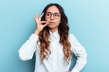 Mavi arka planda izole edilmiş genç Meksikalı kadın parmakları dudaklarında bir sır saklıyor..