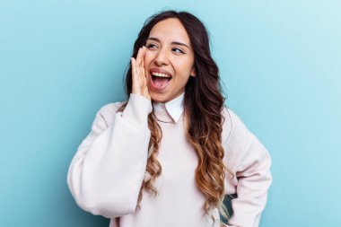 Mavi arka planda izole edilmiş genç Meksikalı kadın heyecanlı bir şekilde bağırıyor..