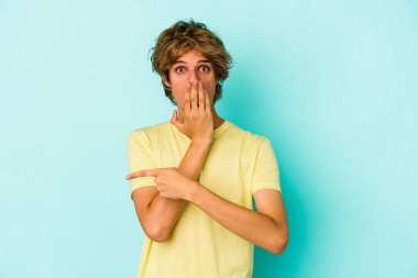 Makyajlı genç beyaz adam, mavi arka planda izole edilmiş.