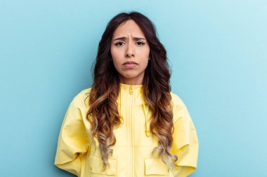 Genç Meksikalı kadın mavi arka planda izole edilmiş üzgün, ciddi yüzlü, mutsuz ve hoşnutsuz..