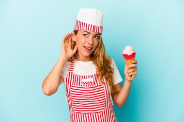 Kafkasyalı dondurma üreticisi kadın elinde dondurmayla mavi arka planda bir dedikoduyu dinlemeye çalışıyor..