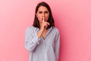 Pembe arka planda izole edilmiş genç beyaz kadın ya sır saklıyor ya da sessizlik istiyor..