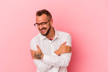 Pembe arka planda izole edilmiş dövmeleri olan beyaz bir adam gülüyor ve eğleniyor..