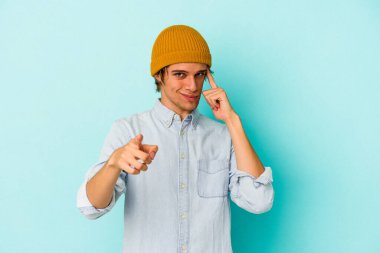 Mavi arka planda soyutlanmış beyaz tenli genç bir adam şakağı parmağıyla işaret ediyor, düşünüyor ve bir göreve odaklanıyor..