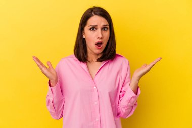 Sarı arka planda izole edilmiş genç beyaz kadın şaşırdı ve şok oldu..