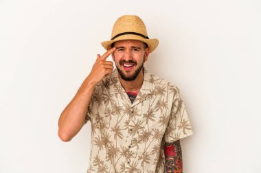 Beyaz arka planda izole edilmiş yazlık giysiler giyen beyaz dövmeli genç beyaz bir adam işaret parmağıyla yaptığı hayal kırıklığını gösteriyor..