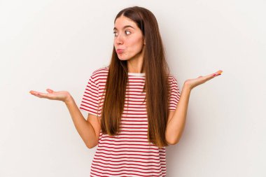 Beyaz arka planda izole edilmiş genç beyaz bir kadın. Kafası karışmış ve omuz silkiyor. Kopya alanını tutmak için..