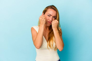 Kafkasyalı kadın mavi arka planda izole edilmiş. Yumruk atıyor, sinirleniyor, kavga ediyor, kavga ediyor..