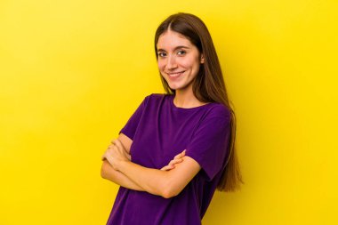 Sarı arka planda izole edilmiş genç beyaz bir kadın. Kendini güvende hissediyor. Kararlı bir şekilde kollarını kavuşturuyor..