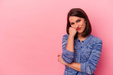 Pembe arka planda izole edilmiş genç beyaz kadın üzgün ve düşünceli, fotokopi alanına bakıyor..