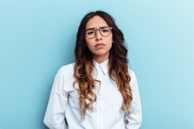 Genç Meksikalı kadın mavi arka planda izole edilmiş üzgün, ciddi yüzlü, mutsuz ve hoşnutsuz..