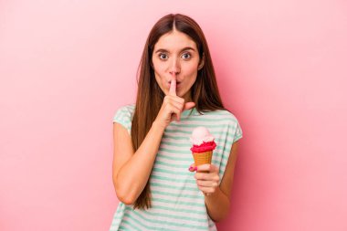 Pembe arka planda izole edilmiş dondurma tutan beyaz bir kadın ya sır saklıyor ya da sessizlik istiyor..