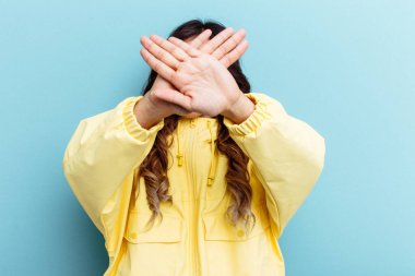 Mavi arka planda izole edilmiş genç Meksikalı kadın iki kolu çapraz tutuyor, inkar kavramı.