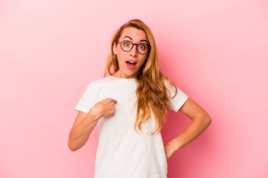 Kafkasyalı sarışın kadın pembe arka planda izole edilmiş. Parmakla işaret ederek şaşırmış, geniş bir gülümsemeyle..