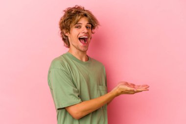 Pembe arka planda soyutlanmış beyaz makyajlı genç bir adam. Elinde palmiye ağacında bir fotokopi odası var..