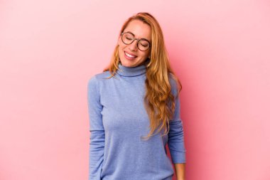 Beyaz tenli sarışın kadın pembe arka planda izole edilmiş. Kahkahalar atıyor ve gözlerini kapatıyor. Rahatlamış ve mutlu hissediyor..