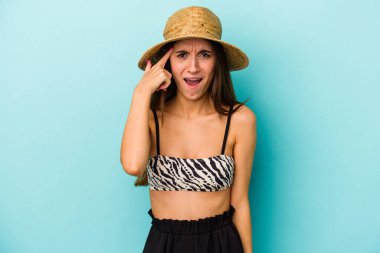 Mavi arka planda izole edilmiş bikini giyen beyaz bir kadın işaret parmağıyla yaptığı hayal kırıklığı jestini gösteriyor..