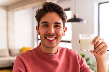 Genç melez adam kahvaltıda süt içiyor.