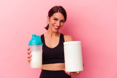 Pembe arka planda izole edilmiş protein içeceği içen beyaz bir kadın.
