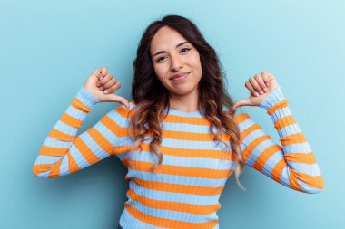 Mavi arka planda izole edilmiş genç Meksikalı kadın gururlu ve kendinden emin hissediyor, örnek olarak.