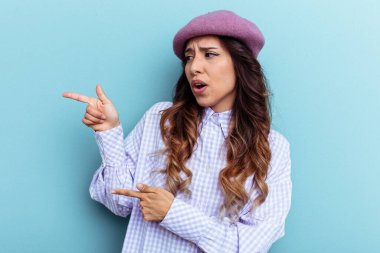 Mavi arka planda izole edilmiş genç Meksikalı kadın işaret parmaklarıyla fotokopi alanını işaret ederek heyecan ve arzusunu ifade ediyor..