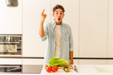 Genç melez adam öğle yemeği için salata hazırlıyor. Bir fikri, ilham konsepti var..