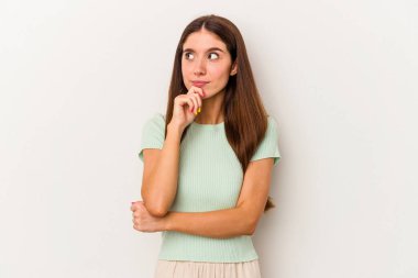 Beyaz arka planda izole edilmiş genç beyaz kadın rahatlamış bir şeyin fotokopi odasına baktığını düşünüyor..