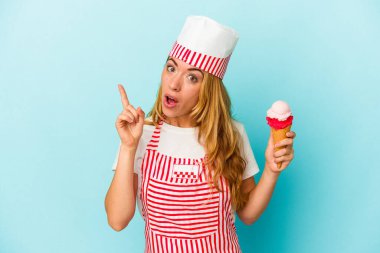 Kafkasyalı dondurma üreticisi kadın elinde dondurmayla mavi arka planda izole bir şekilde duruyor. Bir fikri, ilham verici bir fikri var..