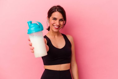 Pembe arka planda izole edilmiş protein içeceği içen beyaz bir kadın.