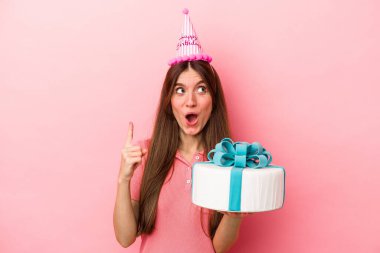 Pembe arka planda izole edilmiş, ağzı açık, beyaz bir kadın doğum gününü kutluyor..