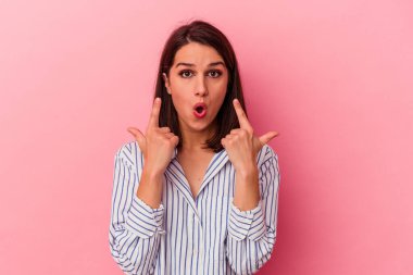 Pembe arka planda izole edilmiş beyaz bir kadın ağzı açık bir şekilde üst tarafı işaret ediyor..