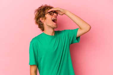 Pembe arka planda soyutlanmış beyaz makyajlı genç bir adam mutlu bir şekilde ellerini başının üstünde tutarak gülüyor. Mutluluk kavramı.