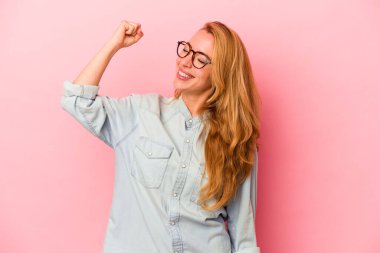 Pembe arka planda izole edilmiş beyaz bir kadın zaferi, tutkuyu ve coşkuyu kutluyor, mutlu bir ifade..