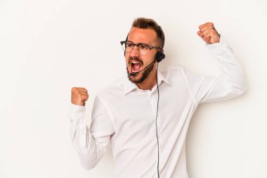 Beyaz arka planda izole dövmeleri olan beyaz pazarlamacı genç adam zafer kazandıktan sonra yumruğunu kaldırıyor..